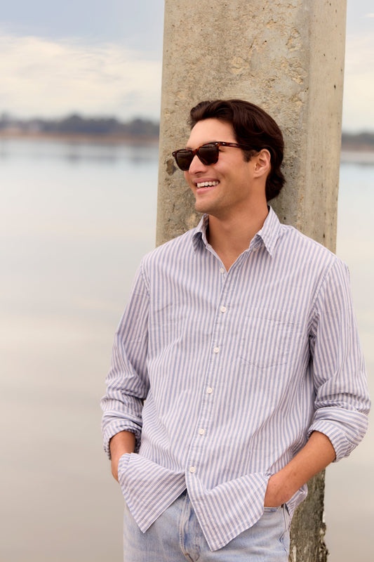 man. leaning against a post in sunglasses