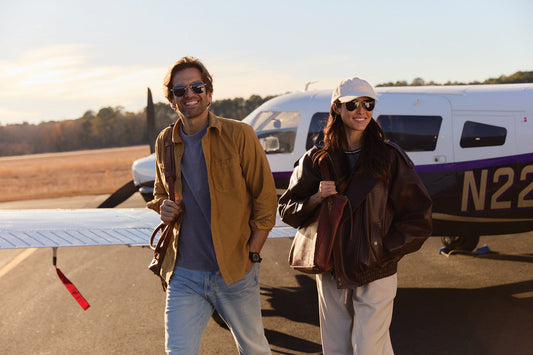 man and woman in aviator sunglasses next to cessna on runway