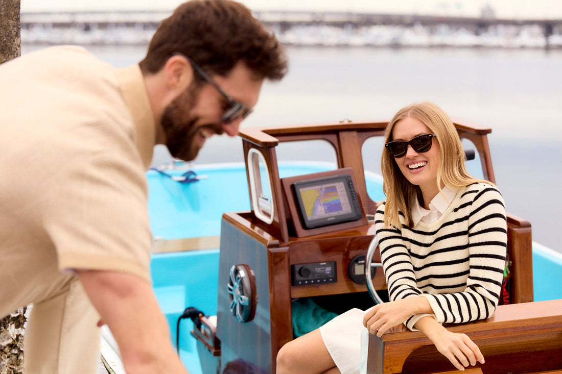 couple wearing sunglasses and smiling in a small boat on the water 