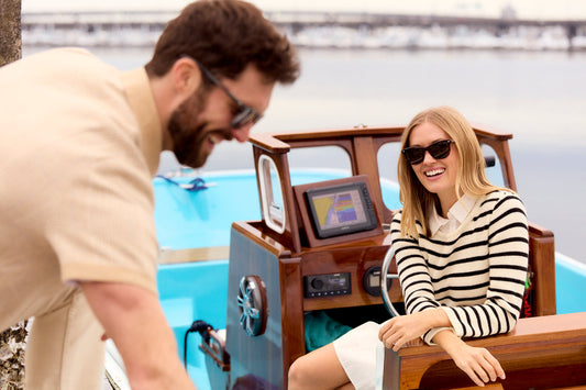 couple wearing sunglasses and smiling in a small boat on the water 
