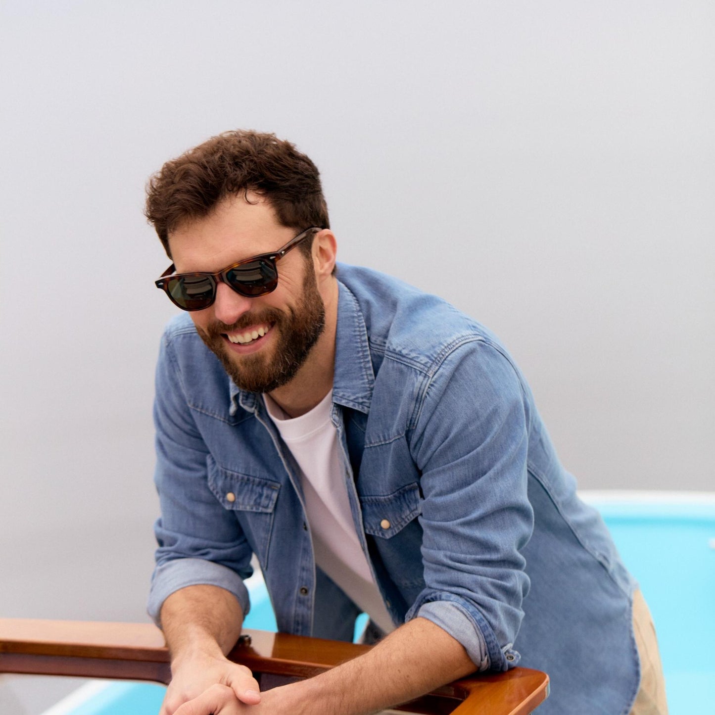Lifestyle Image: Man wearing sunglasses and a denim jacket by a pool
