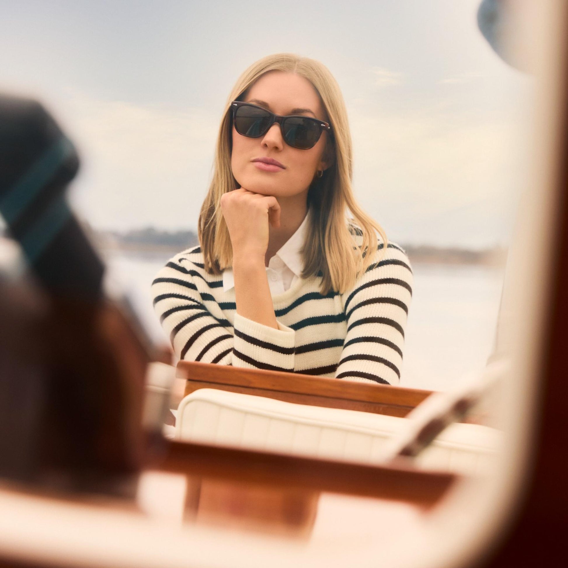 Lifestyle Image: Woman wearing sunglasses and a striped sweater on a boat